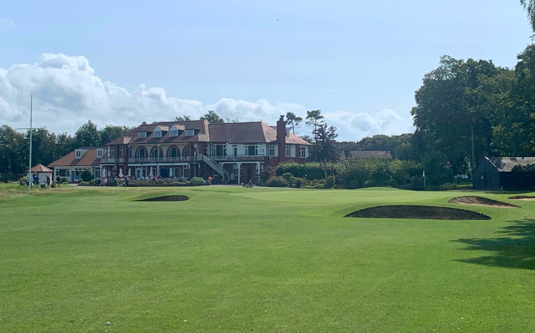The Fairhaven clubhouse behind the green and its bunkers, under a blue sky