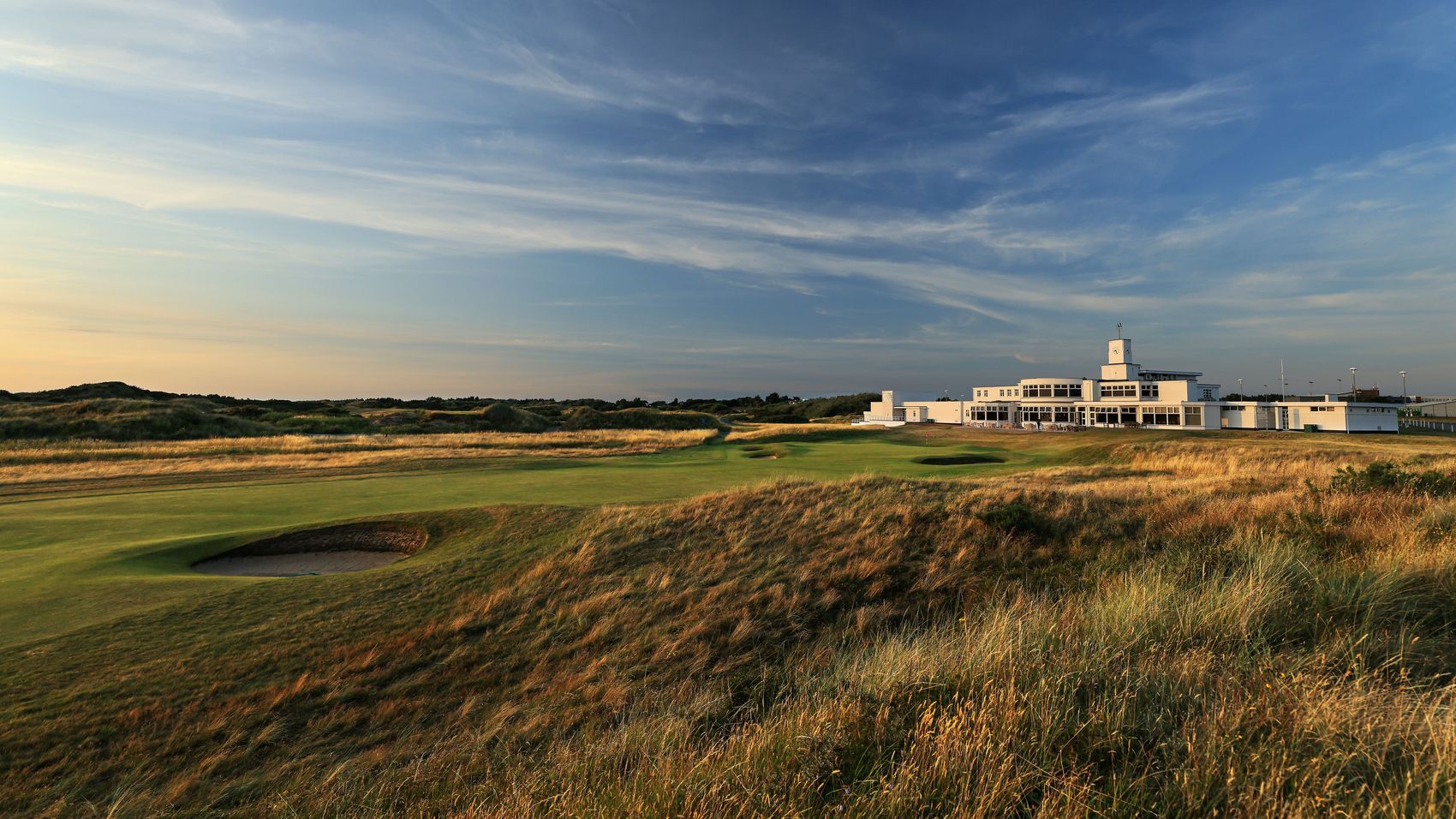 Royal Birkdale's white Art Deco clubhouse across the links at sunset