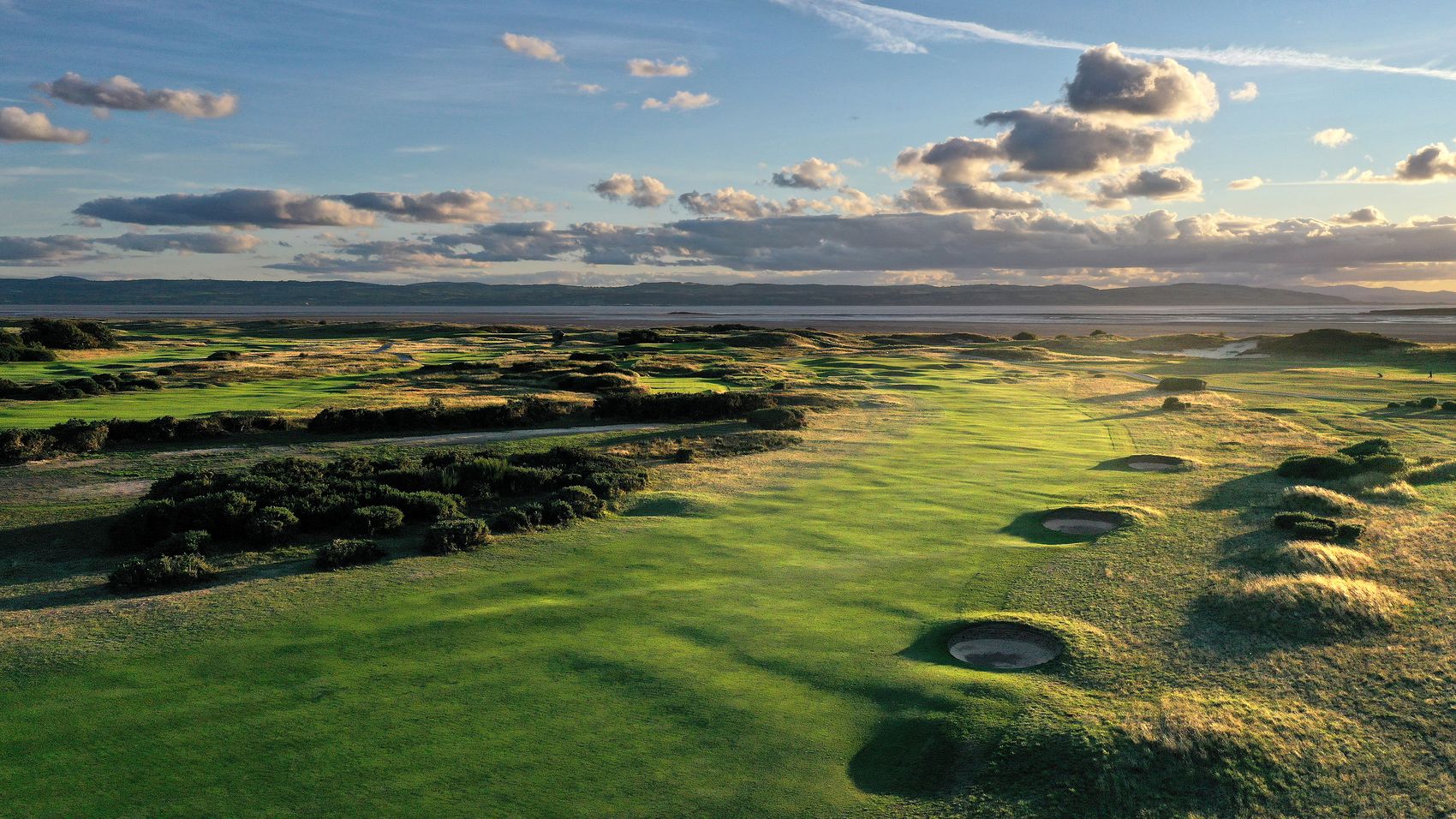 Aerial view of a Royal Liverpool fairway and pot bunkers, with the estuary and distant hills beyond